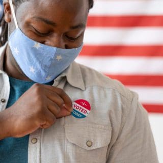African American man wearing a mask with an I Voted sticker